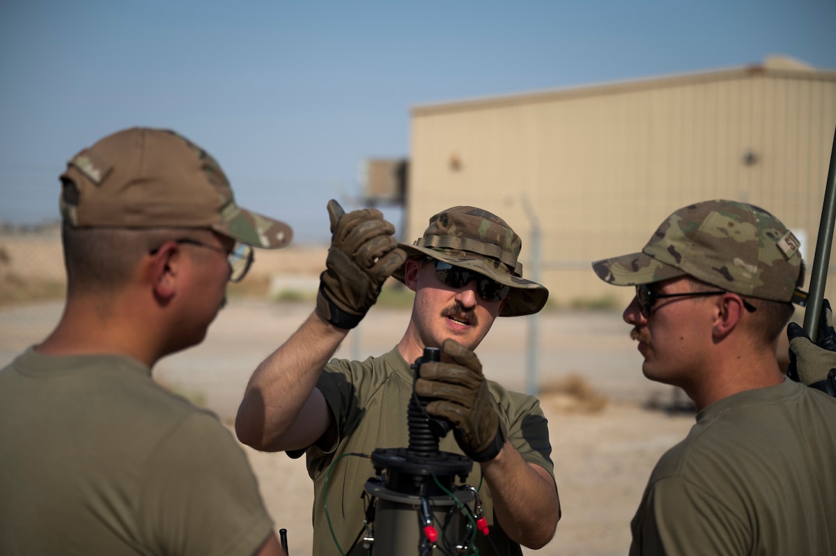 U.S. Air Force Tech. Sgt. Henry Lawler, 378th Expeditionary Communications Squadron SCOT section chief, teaches Senior Airman Joseph Lee, 386th Expeditionary Communications Squadron cyber transport technician and Senior Airman Daniel Stricker, 386th ECS Radio Frequency transmission technician, how to install a mast communications system Operation Agile Spartan III at an undisclosed location, September 12, 2022. The mast communications system is a portable communications system that a minimum of three Airmen can set up to strengthen communications quickly. (U.S. Air Force photo by Staff Sgt. Dalton Williams)
