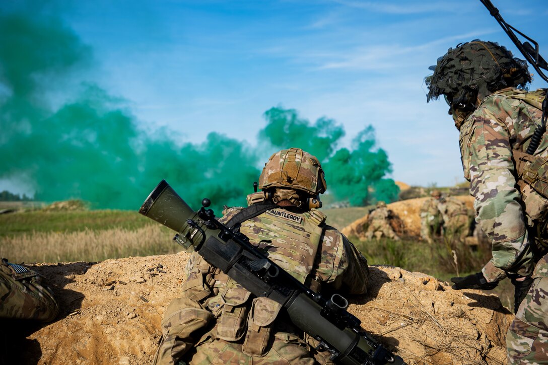 Two soldiers observe green smoke targets.