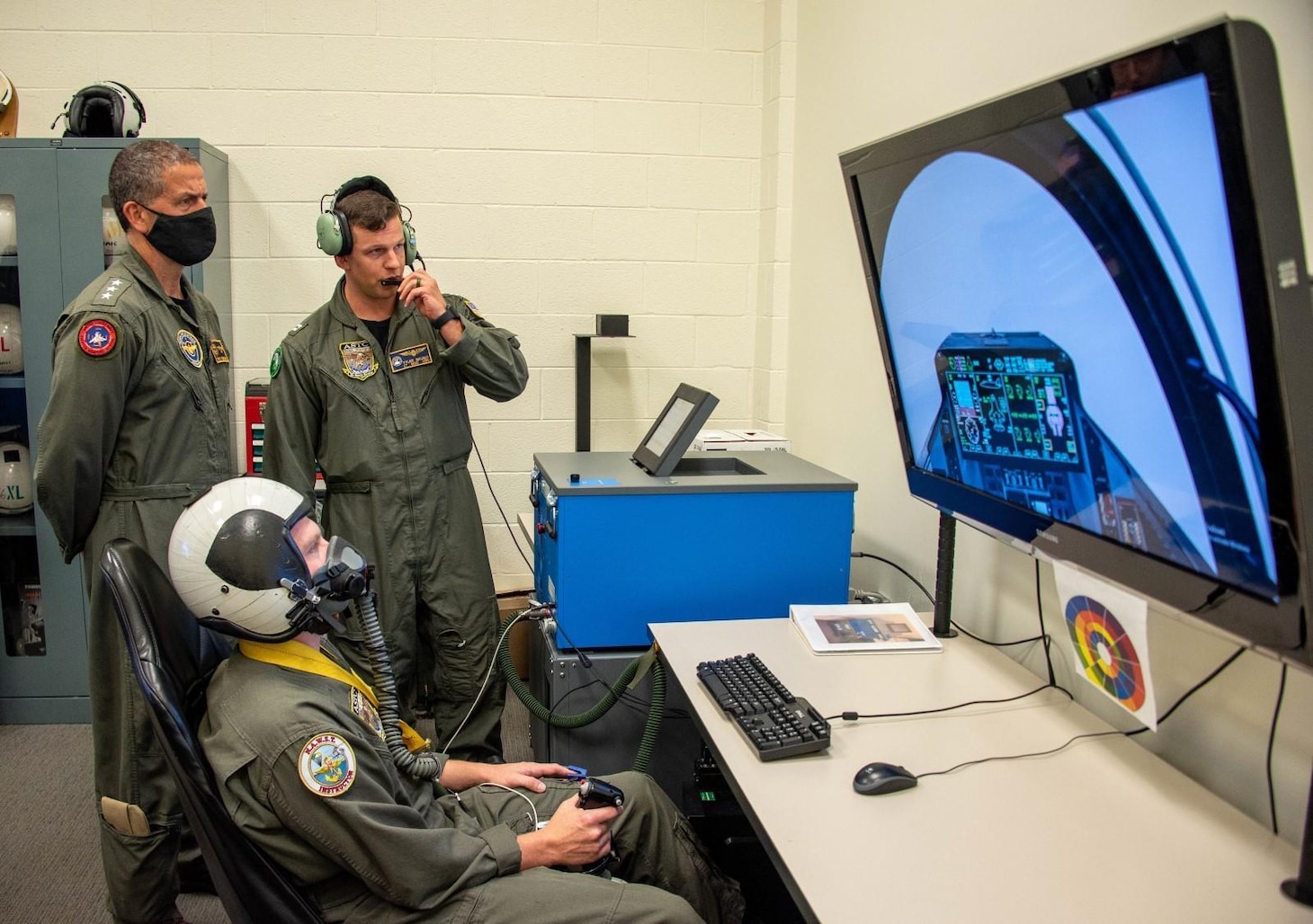 NAVAIR Commander Vice Adm. Carl Chebi (left) gets a firsthand look at the Mask on Breathing Device (MOBD) trainer July 7 at the Patuxent River Aviation Survival Training Center (ASTC). Flight Physiologist Lt. Tyler Grubic (right) demonstrated the effect of the different breathing distress profiles on subject Electronic Warfare Systems Specialist 1 Shawn Bell (center). The MOBD trainer will be available at all eight ASTC locations later this year.