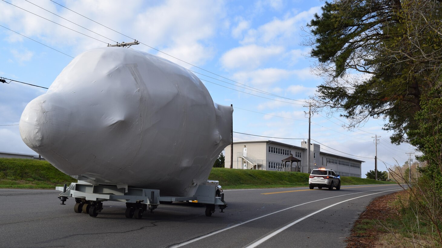 A massive, Navy C-130 Communications/Navigation/Instrumentation (CNI) candidate training device is towed to the Patuxent River Naval Air Museum