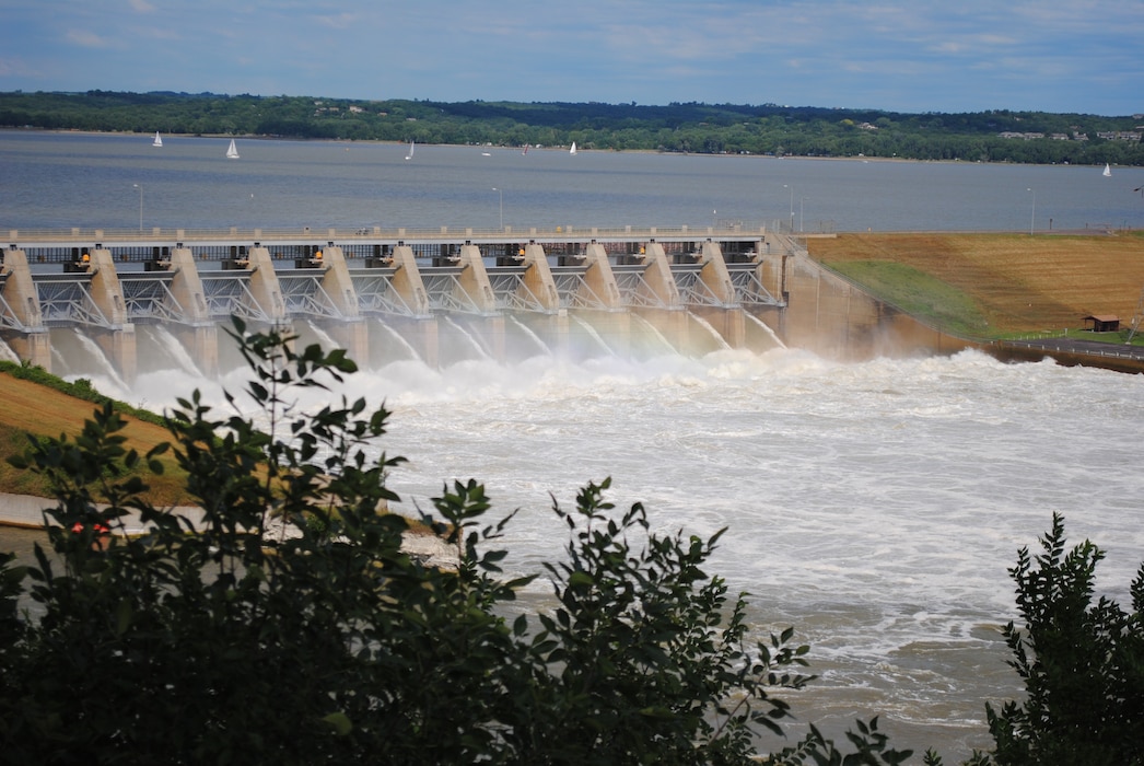 water cascades out of the spillway gate into a river with a slight rainbow effect