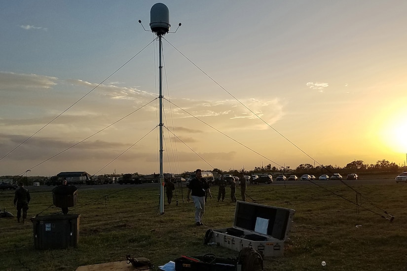 A large piece of equipment is tethered to a field at sunset.