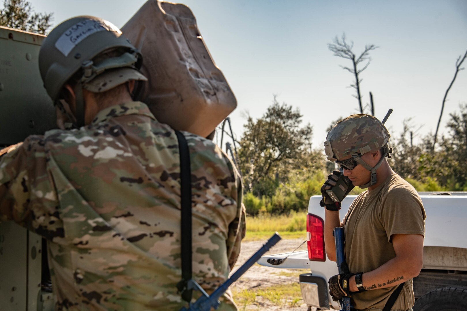 an Airman talks into a radio as another fills a generator with gas