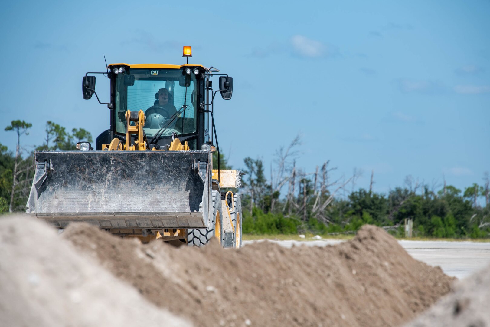 a bulldozer approaches a pile of dirt