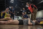 An emergency medical technician (far left) explains her evaluation of a simulated casualty during a Regional Emergency Medical Services System training event at the Choctaw Event Center in Durant, Oklahoma, September 21, 2022. A total of around 170 first responders participated in this annual training event. (Oklahoma National Guard Photo by Sgt. Reece Heck)