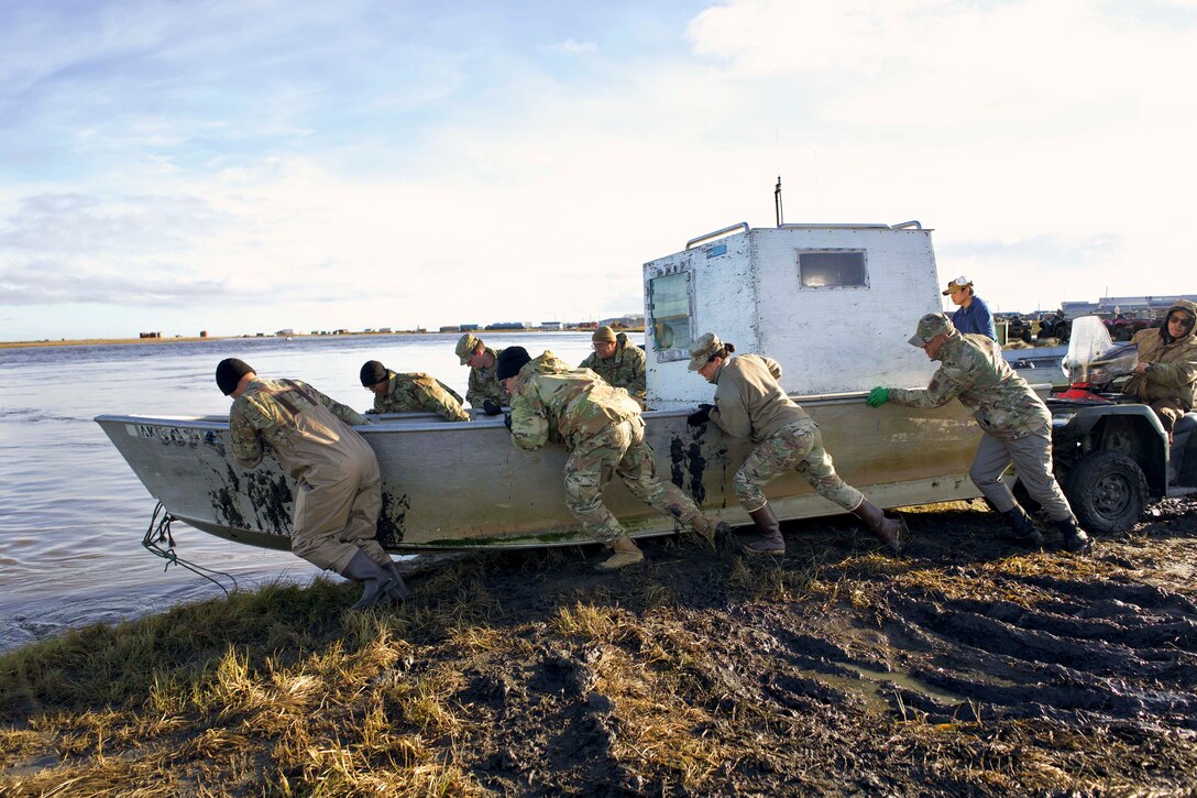 National Guardsmen move a small boat from mud into water.
