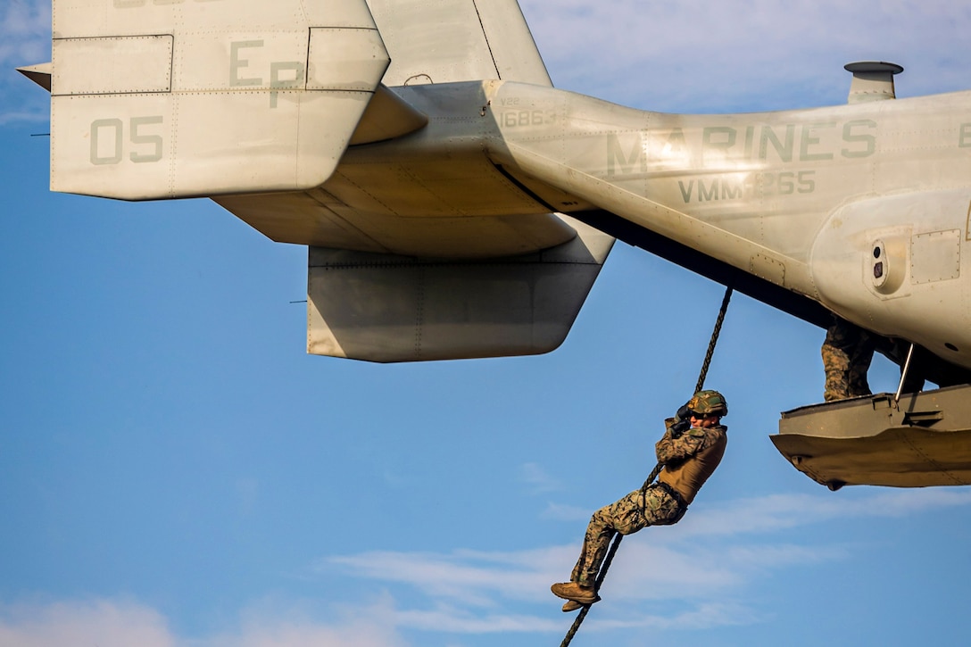 A Marine fast-ropes out of an airborne helicopter.