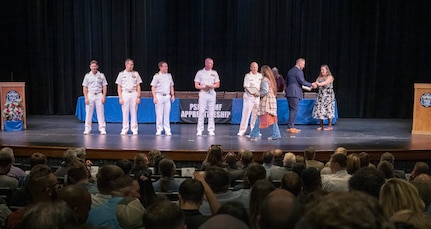 Apprentice Program graduates receive congratulations from (r to l) Capt. Jip Mosman, commander, Puget Sound Naval Shopyard & Intermediate Maintenance Facility; Capt. David Hanthorn, production resources officer, Code 900; Capt. Mike Eberlein, commanding officer, Trident Refit Facility Bangor; Capt. Clint Hoskins, commanding officer, Naval Undersea Warfare Center Keyport; and Lt. Cmdr. Joseph Zukowsky, production officer, Naval Facilities Engineering Systems Command Northwest, during the Puget Sound Naval Shipyard & Intermediate Maintenance Facility Apprentice Program graduation ceremony held Sept. 23, 2022, at the Bremerton High School Performing Arts Center, in Bremerton, Wash. (U.S. Navy photos by Wendy Hallmark)