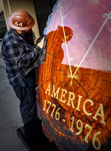 A Shop 64 employee at Puget Sound Naval Shipyard & Intermediate Maintenance Facility polishes the newly restored PSNS & IMF Bicentennial Log before it is placed in its new location in the lobby of Building 850 at PSNS & IMF, in Bremerton, Wash. (U.S. Navy photo by Wendy Hallmark)