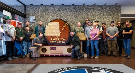 2021-2022 restoration project team members from Shops, 64, 26, 11 and 71, pose with Capt. Jip Mosman, commander, Puget Sound Naval Shipyard & Intermediate Maintenance Facility by the newly restored Bicentennial log. The log was unveiled by Mosman and Jason Beller, Code 964 Trade Superintendent during a short ceremony held on Sept. 13, 2022, at it's new "home" in the lobby of Building 850 at PSNS & IMF, in Bremerton, Wash. (U.S. Navy Photo by Wendy Hallmark)