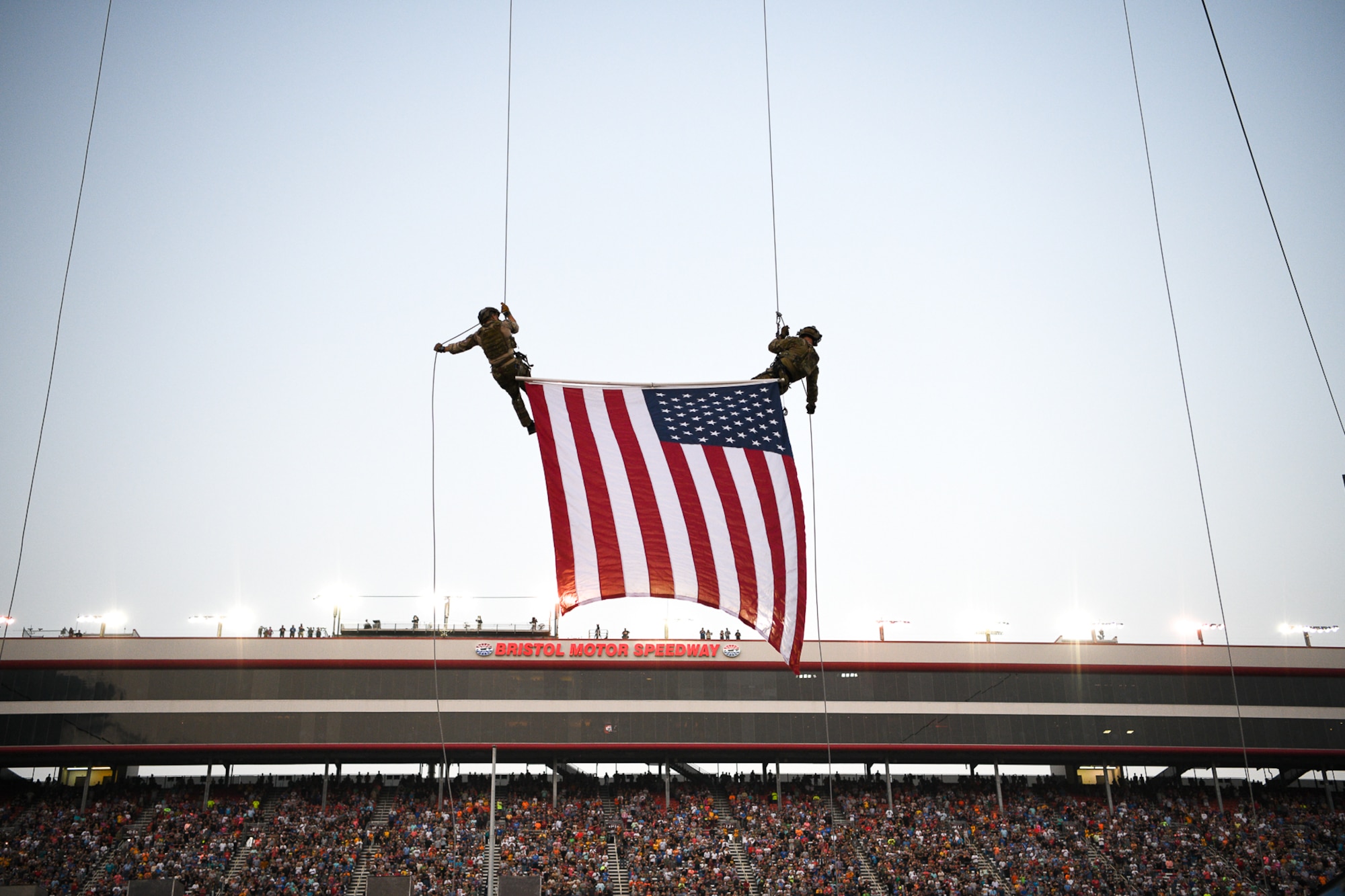 Two rappelers descend with the U.S. flag.