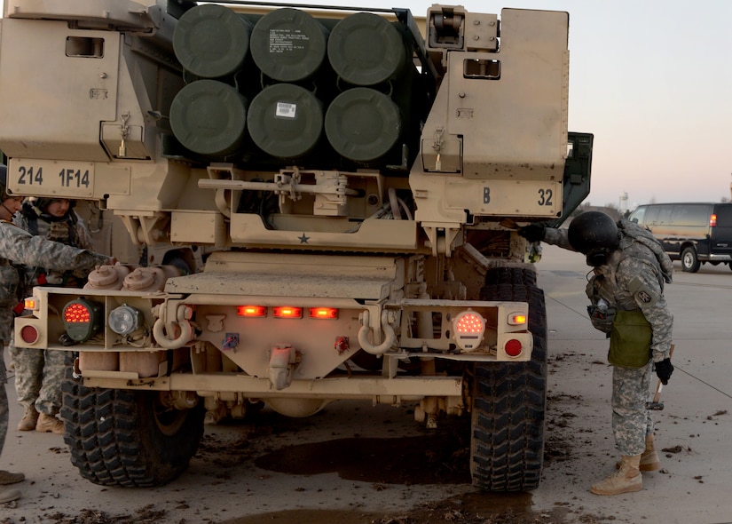 A service member inspects a large military vehicle.