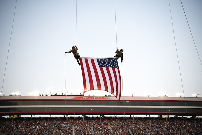 Two rappelers descend with the U.S. flag.