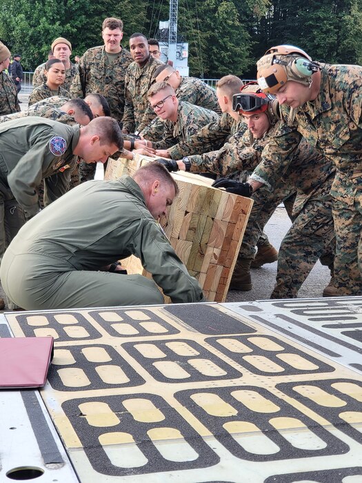 Reserve Citizen Airmen assigned to the 68th Airlift Squadron and Marines with the Marine Light Attack Helicopter Squadron – 773, Det. Alpha move wooden planks into place to assist with loading two Marine helicopters onto a C-5M Super Galaxy aircraft Sept. 13, 2022, at Naval Air Station Joint Reserve Base New Orleans, Louisiana. The aircraft and helicopters were on display during the 22nd NATO Days air show in Ostrava, Czech Republic, Sept. 17-18, 2022. (U.S. Air Force photo by Minnie Jones)