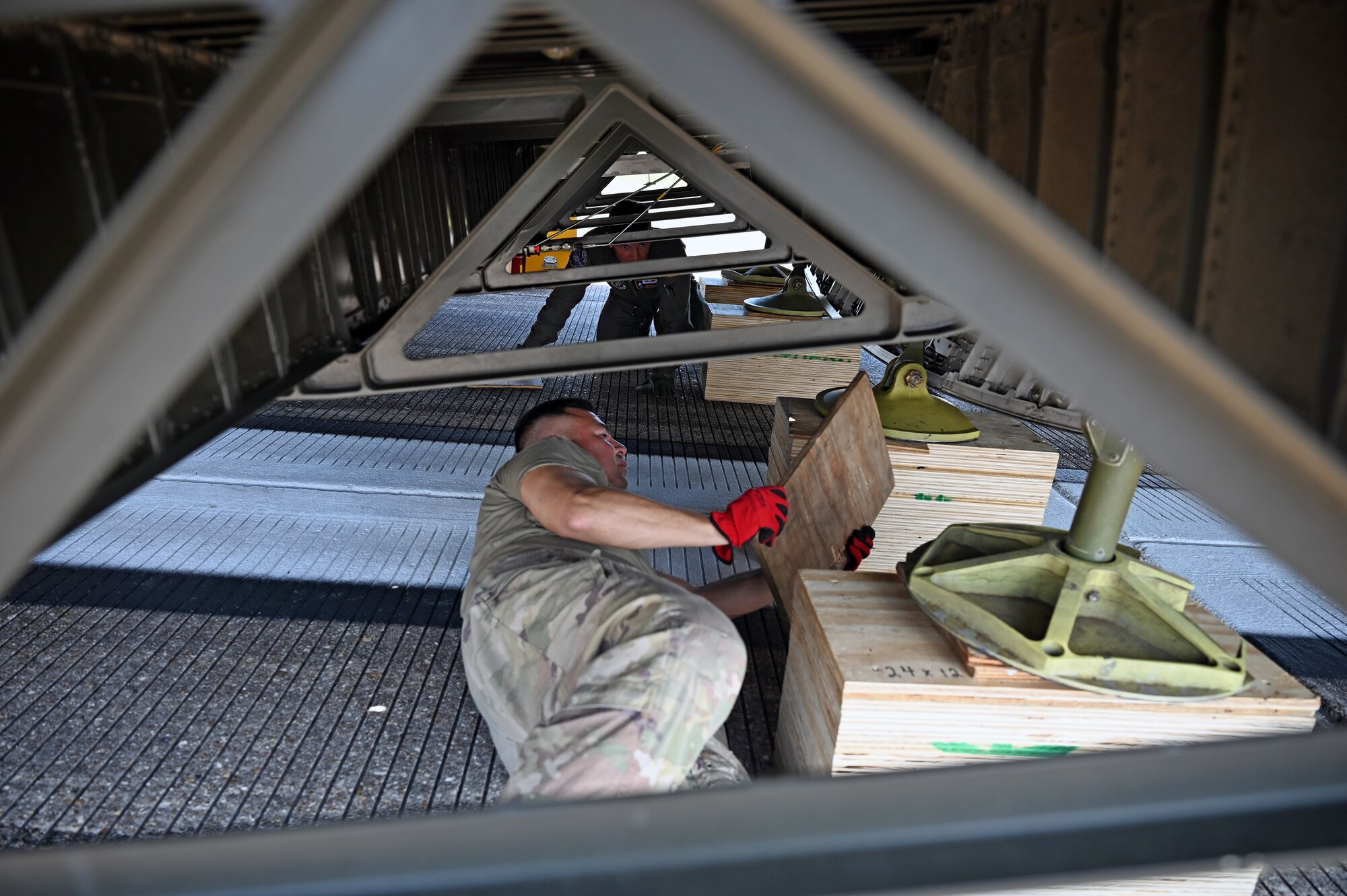 Reserve Citizen Airmen with the 68th Airlift Squadron place wooden supports under the ramp of a C-5M Super Galaxy aircraft at Naval Air Station Joint Reserve Base New Orleans, Louisiana, Sept. 13, 2022. Marines in the Marine Light Attack Helicopter Squadron – 773, Det. Alpha specifically engineered the wooden boxes and planks to load and offload two helicopters, the Bell AH-1Z Viper and UH-1Y Venom, onto the C-5M Super Galaxy aircraft. (U.S. Air Force photo by Staff Sgt. Monet Villacorte)