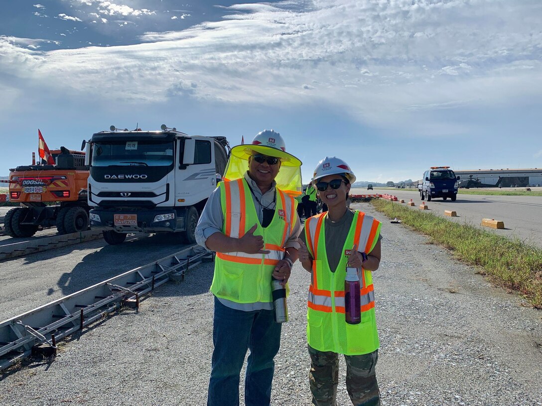 Lauren Wougk (right), a Department of Army intern, poses with a colleague, Ricky Aquino (left), Far East District construction control representative, at the project site for Type II Aircraft Parking Apron and Taxiway located at U.S. Army Garrison Humphreys. Wougk recently completed her intern rotation at the Far East District. (U.S. Army photo by U.S. Army Corps of Engineers Far East District)