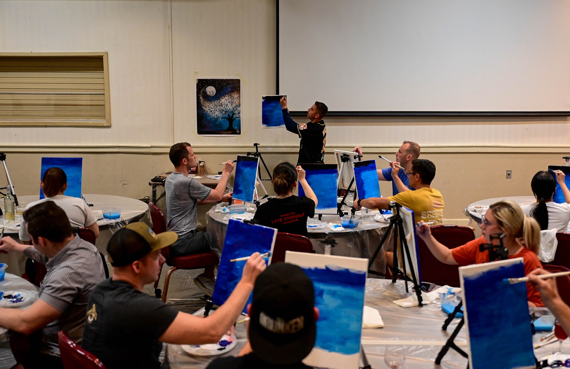 Students follow instructor guidance while painting.