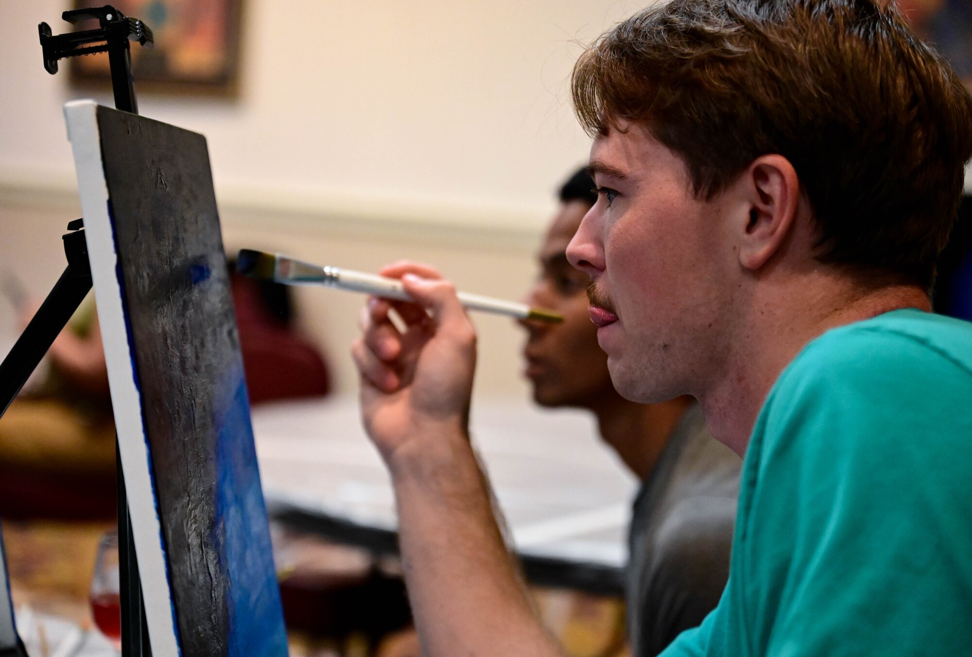 Man licks his lip as he paints