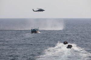 GULF OF OMAN (Sept. 28, 2022) An interdiction team from guided-missile destroyer USS Delbert D. Black (DDG 119) approaches a fishing vessel in the Gulf of Oman, Sept. 28, as an MH-60R Sea Hawk attached to Helicopter Maritime Strike Squadron (HSM) 48 provides aerial support.