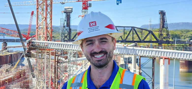 Kyle Phillips stands in front of Chickamauga Lock smiling and wearing all appropriate safety equipment.