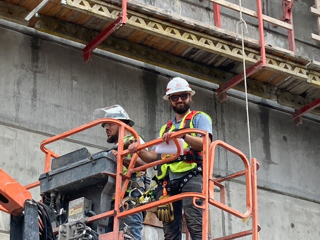 Kyle Phillips stands with another male engineer inside of a fully elevated basket crane.