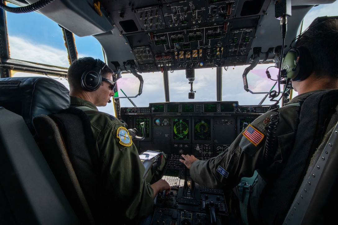 Two pilots sit in the cockpit and pilot an aircraft.