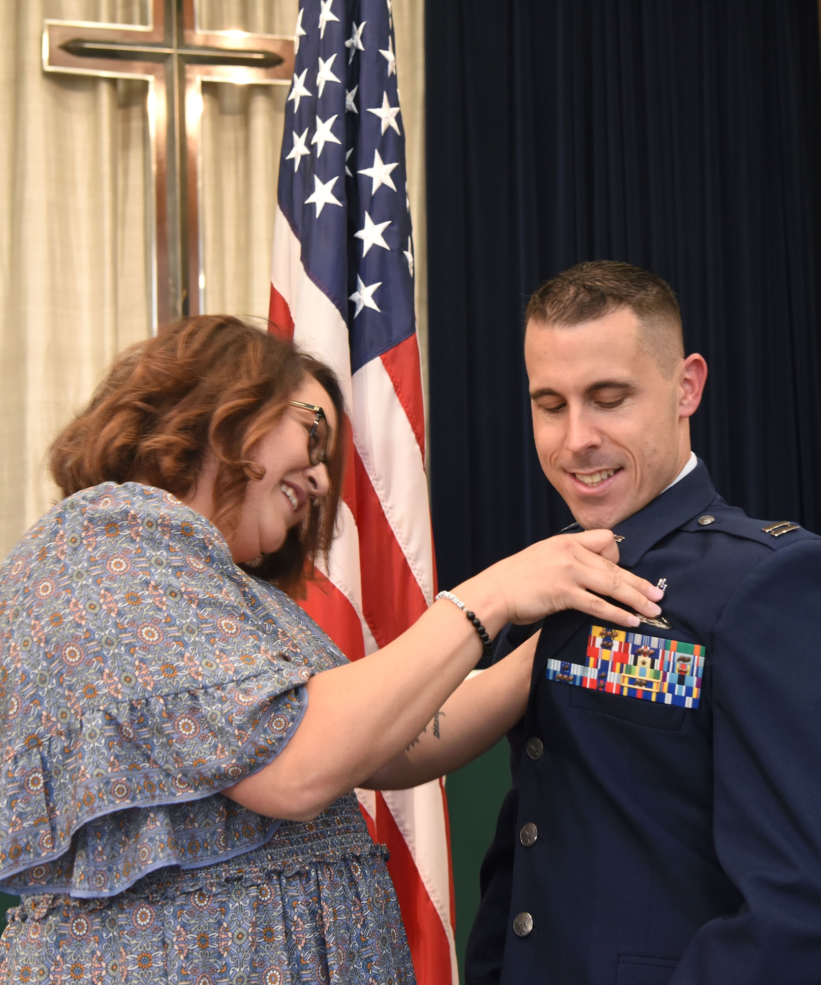 U.S. Air Force Capt. Terry Owens, right, formerly 100th Aircraft Maintenance Squadron director of operations, has the chaplain career field badge pinned on his jacket by his wife Casandra, during a recommissioning ceremony at Royal Air Force Lakenheath, England, Sept. 27, 2022. Owens started his military career as an enlisted maintainer in ground radar maintenance, before becoming a maintenance officer. His journey with religion started when he was 10 years old, when he realized it was his calling and eventually began full-time ministry. He decommissioned and recommissioned at the ceremony and is now a captain-chaplain, continuing his calling at F.E. Warren, Wyoming. The religiously oriented private organization that Owens led over the past year was the first of its kind in the Air Force. (U.S. Air Force photo by Karen Abeyasekere)