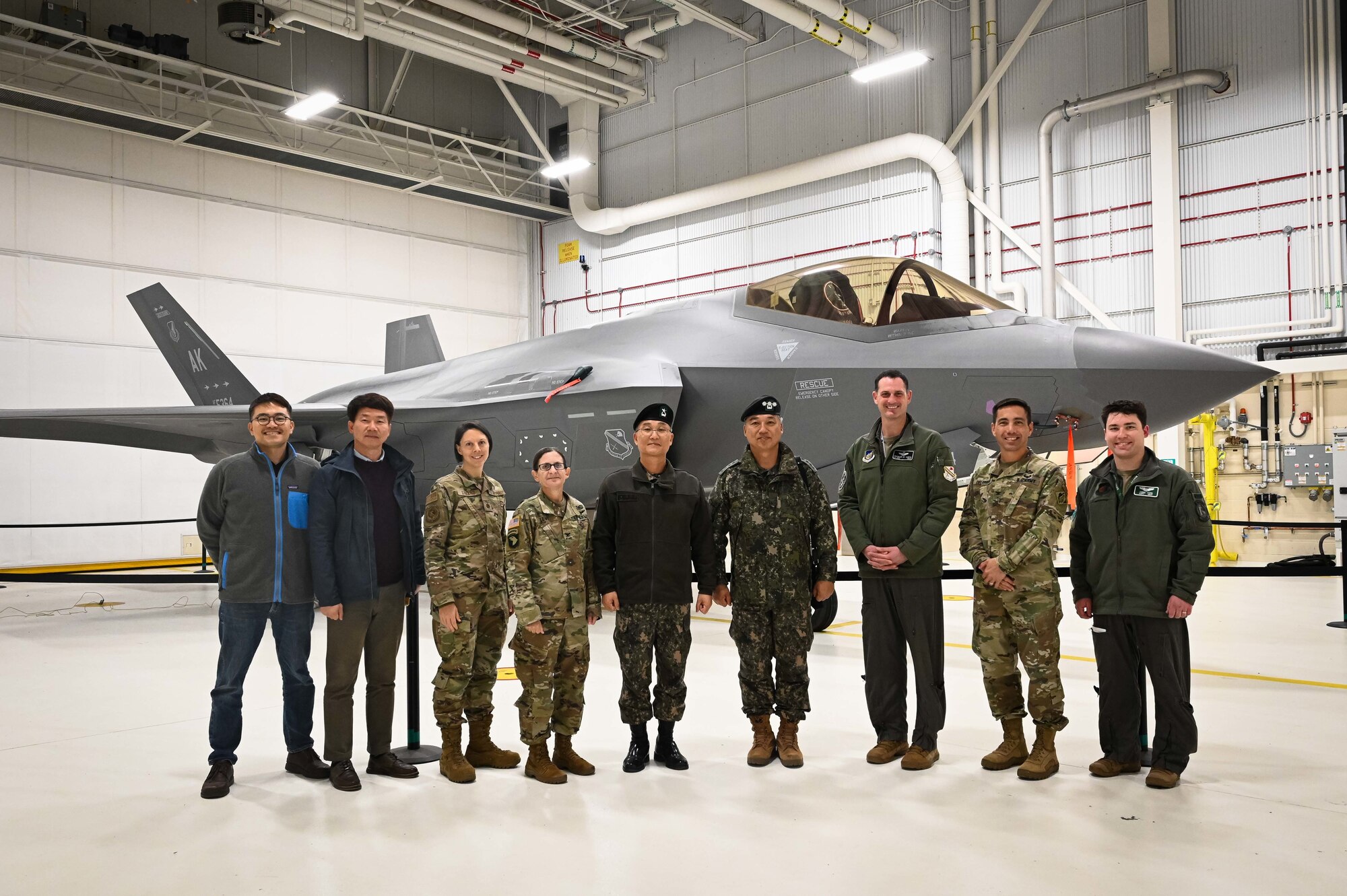 A group of people pose for a photo in front of an F-35