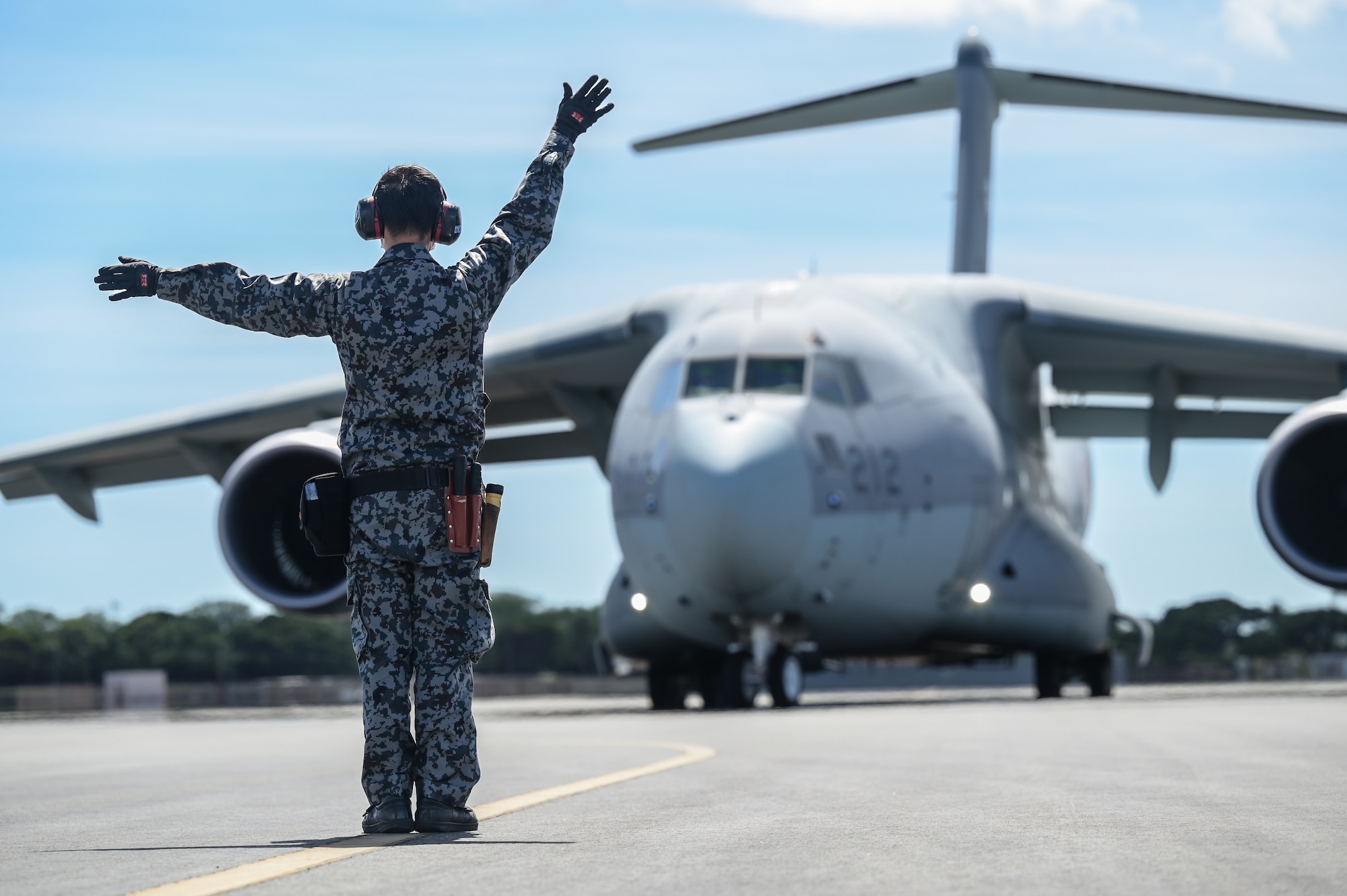 Japan Air Self-Defense Force Staff Sgt. Ippei Fujiwara, 3rd Tactical Airlift Wing Maintenance and Supply Group Inspection Squadron airplane general, marshalls a Kawasaki C-2 during bilateral training at Joint Base Pearl Harbor-Hickam, Hawaii, Sept. 26, 2022. The 3-day training focused on interoperability between the C-2 and C17 Globemaster III to identify best practices for future operations within the Indo-Pacific region. (U.S. Air Force photo by Staff Sgt. Alan Ricker)