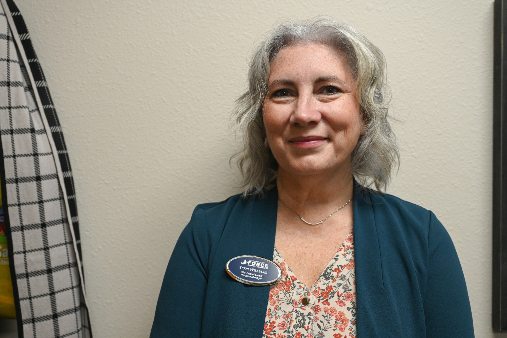 A woman stands in front of a wall to pose or a photo.