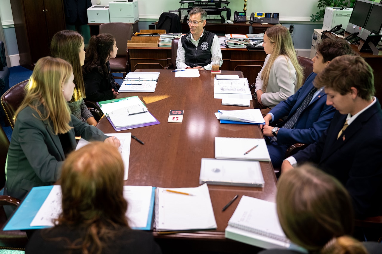 A group of people sit at a conference table.
