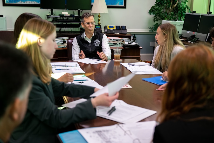 A group of people sit at a conference table.