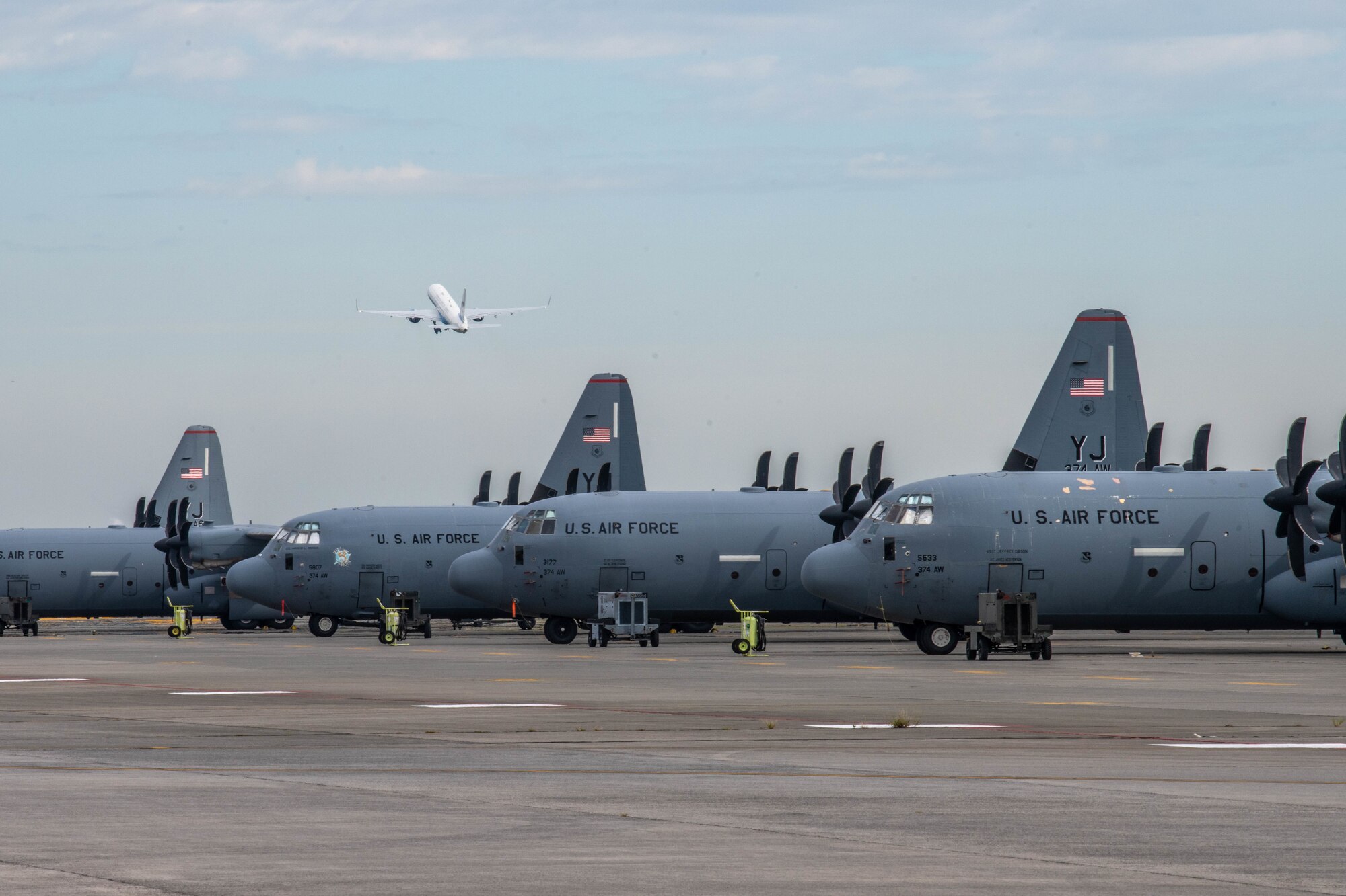 Air Force Two flies over C-130Js parked on the flightline