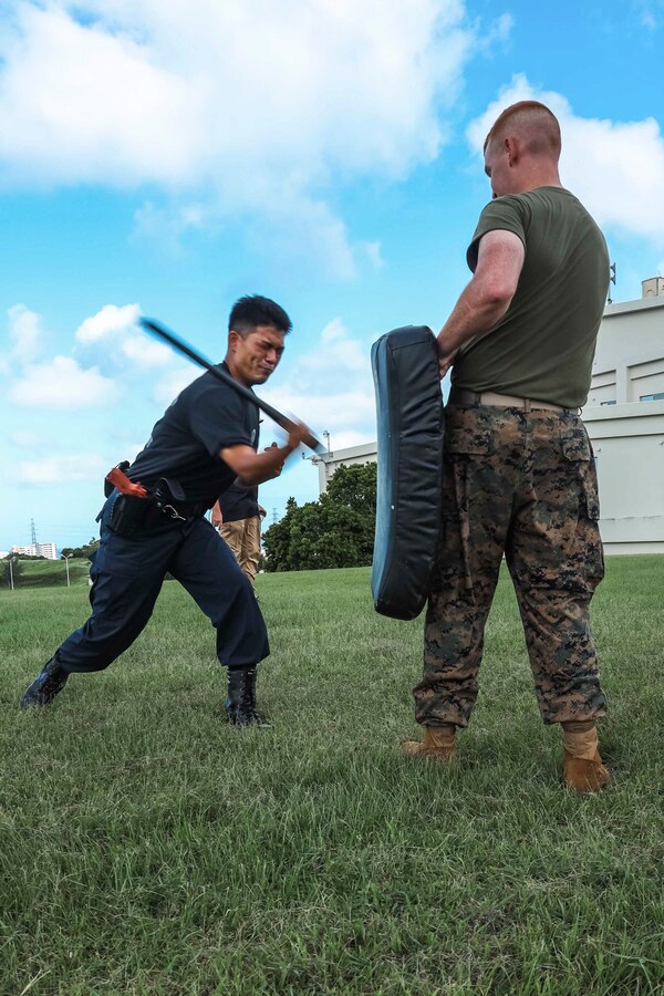 A Japanese Security Guard with Provost Marshal’s Office, Headquarters and Support Battalion, Marine Corps Installations Pacific, strikes a pad with a baton during an oleoresin capsicum spray response training on Camp Foster, Okinawa, Japan, Sep. 16, 2022.  During the Marine-led training, JSGs navigated through an obstacle course while experiencing the effects of OC spray, also known as pepper spray. The training consists of tactics to subdue and arrest a subject and ensures law enforcement personnel understand the effects of the spray. (U.S. Marine Corps photo by Lance Cpl. Jonathan Beauchamp)