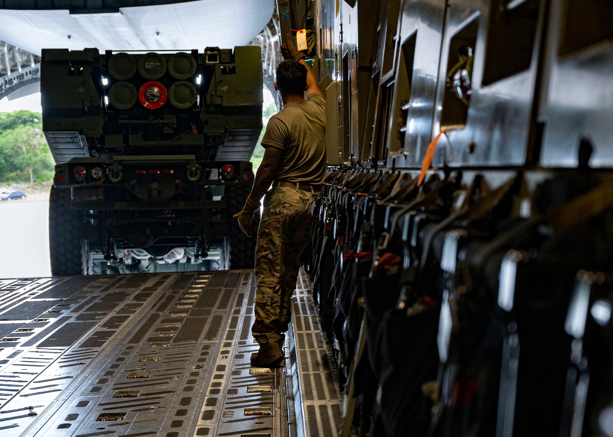 U.S. Air Force Senior Airman Frankie Alan Arceo, Dover Air Force Base, Delaware, 3rd Airlift Squadron loadmaster, directs a High Mobility Artillery Rocket System onto a C-17 Globemaster III during Exercise GOLDEN BEE on Northwest Field, Guam, Sept. 26, 2022. Exercise GOLDEN BEE is a joint readiness exercise designed to provide training integration and rehearse strategic and operational objectives in the Indo-Pacific area of responsibility. (U.S. Air Force photo by Airman 1st Class Lauren Clevenger)