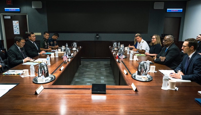 Secretary of Defense Lloyd J. Austin III and other officials converse at a U-shaped table.