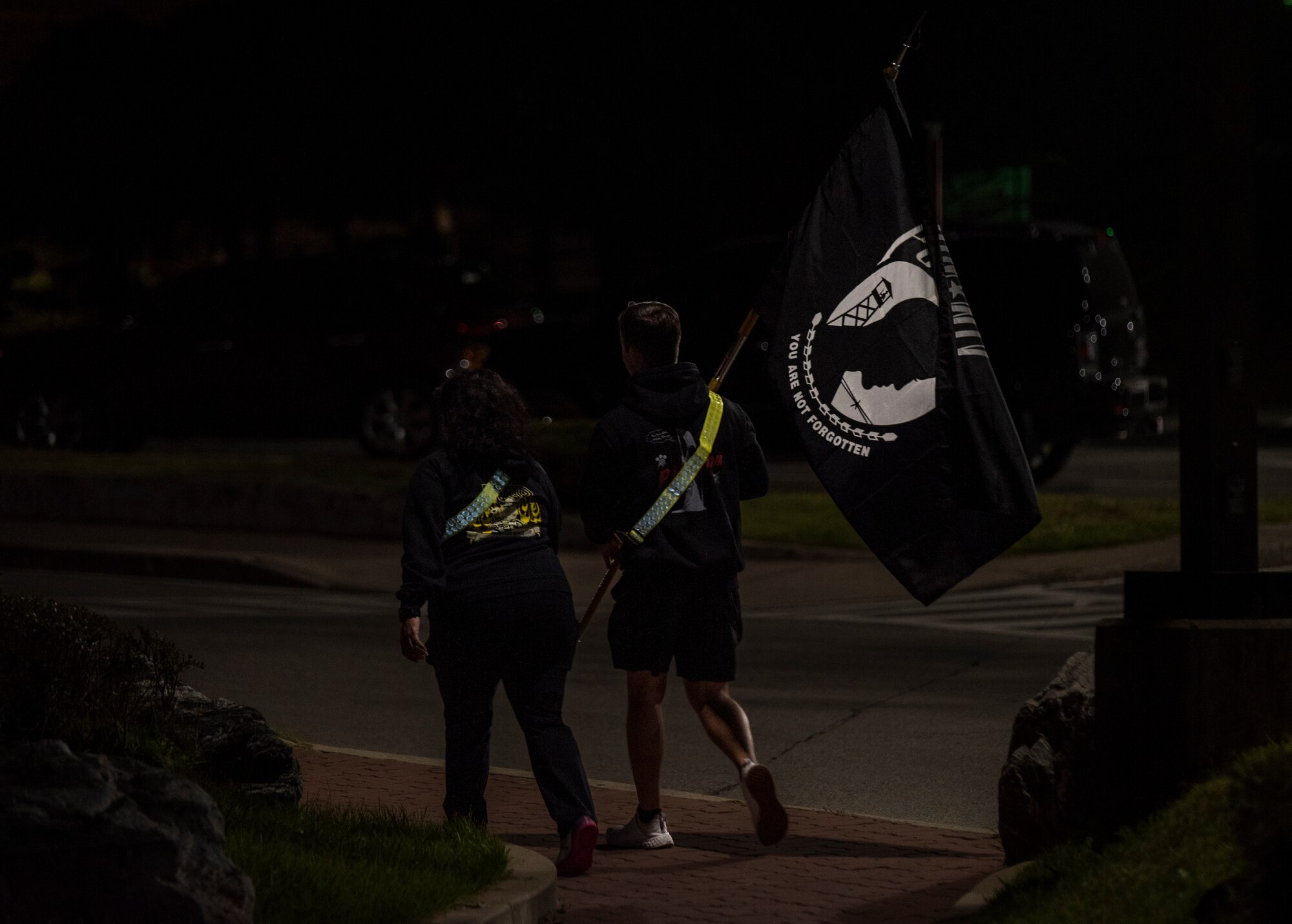 Senior Airmen Hunter Rhoden and Tochtly Silvar, 51st Operations Squadron air traffic controllers, walk with the prisoner of war and missing in action (POW/MIA) guidon during a 24-hour run/walk at Osan Air Base, Republic of Korea, Sept. 26, 2022.