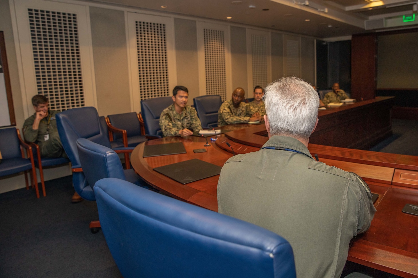 Admiral speaking to Sailors in a conference room