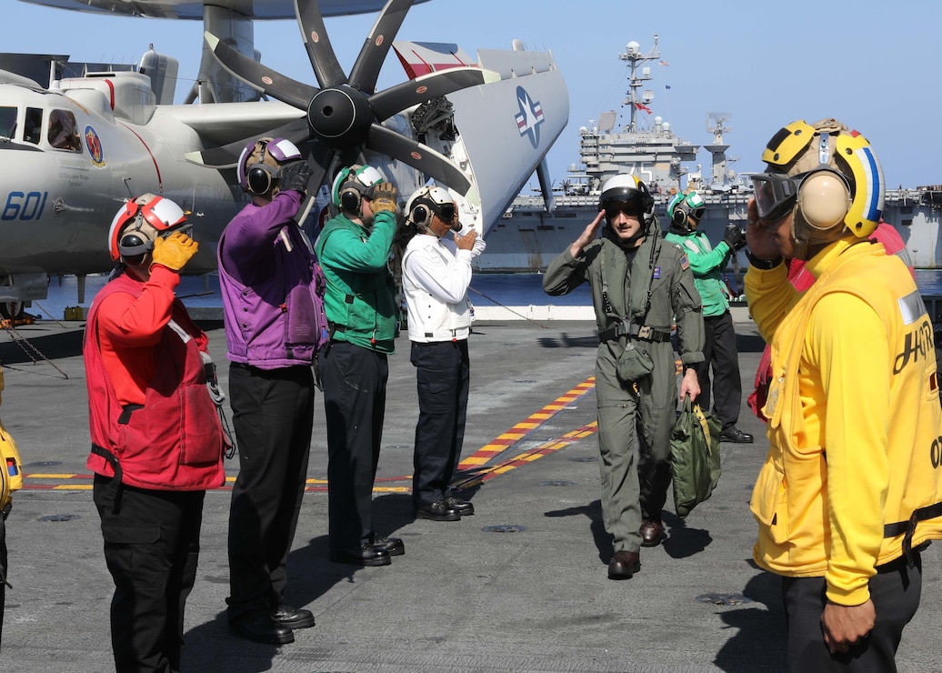 Capt. Patrick Hourigan, commander, Carrier Air Wing (CVW) 1, salutes while walking through rainbow sideboys as he departs the Nimitz-class aircraft carrier USS George H.W. Bush (CVN 77) in the Ionian Sea