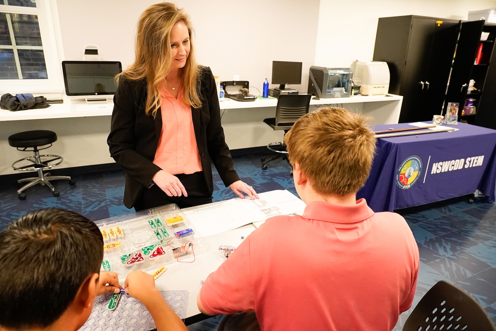 IMAGE: Naval Surface Warfare Center Dahlgren Division (NSWCDD) Chief Technology Officer Jennifer Clift works with a pair of Drew Middle School students as they complete a snap circuit board project during a STEM event at the University of Mary Washington’s (UMW) Seacobeck Hall. NSWCDD partnered with UMW faculty and UMW College of Education students to host the event. (U.S. Navy Photos/Released)