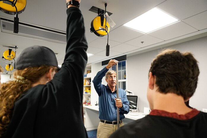 IMAGE: Naval Surface Warfare Center Dahlgren Division (NSWCDD) physicist Scott Gingrich drops a pair of magnets down a stainless steel tube to demonstrate the steel’s lack of ability to conduct electricity during a STEM event for Drew Middle School students at University of Mary Washington’s (UMW) Seacobeck Hall. NSWCDD partnered with UMW faculty and the UMW College of Education students to host the event.