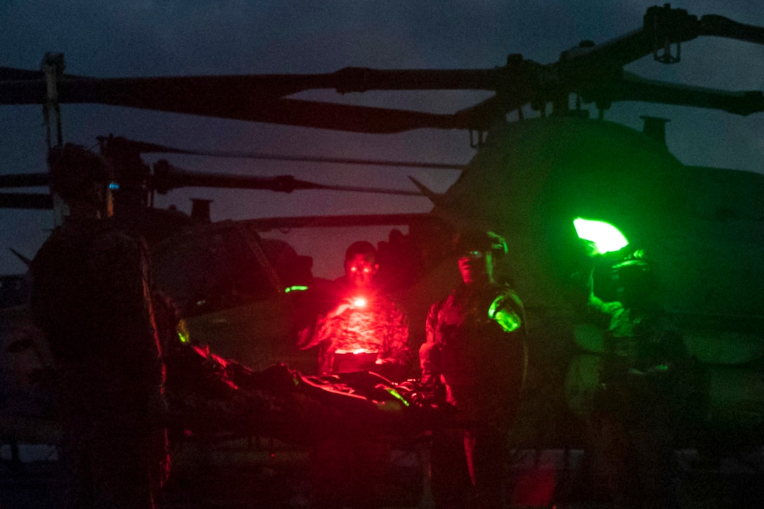 Marines use lights to evacuate a simulated casualty at night.