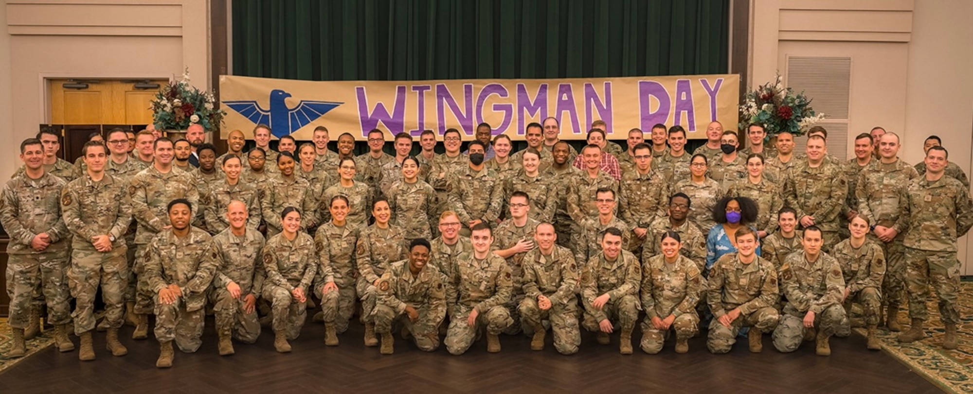 A large group of Airmen pose for a photo in a room.