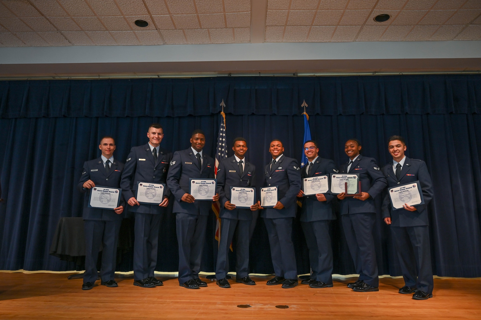 Airmen pose for a photo with graduation certificate.
