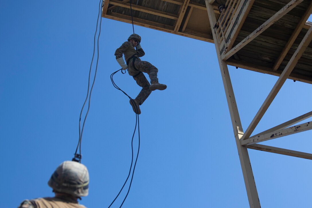 A Marine rappels down a tower.