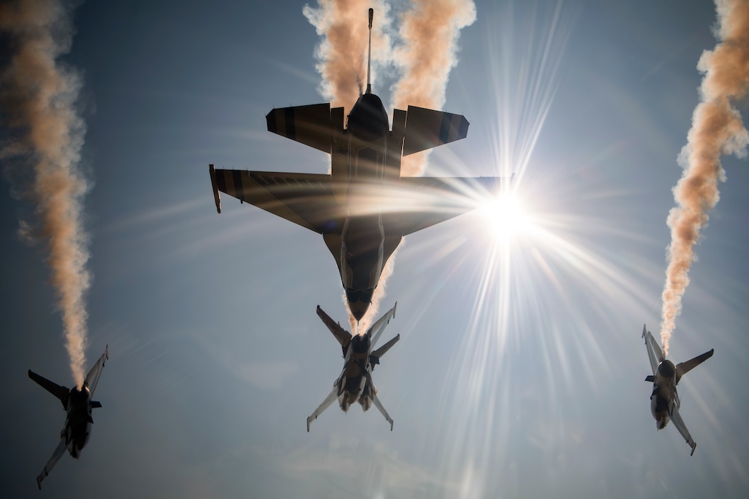 Four aircraft fly in formation while releasing smoke.