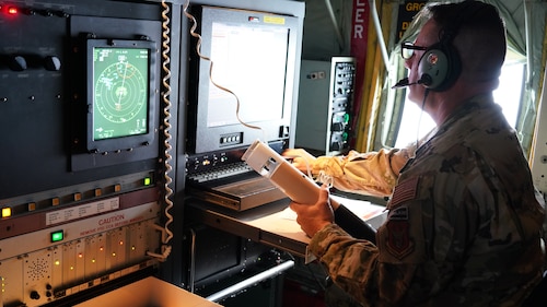 A loadmaster sits in front a computer monitor on a WC-130J.