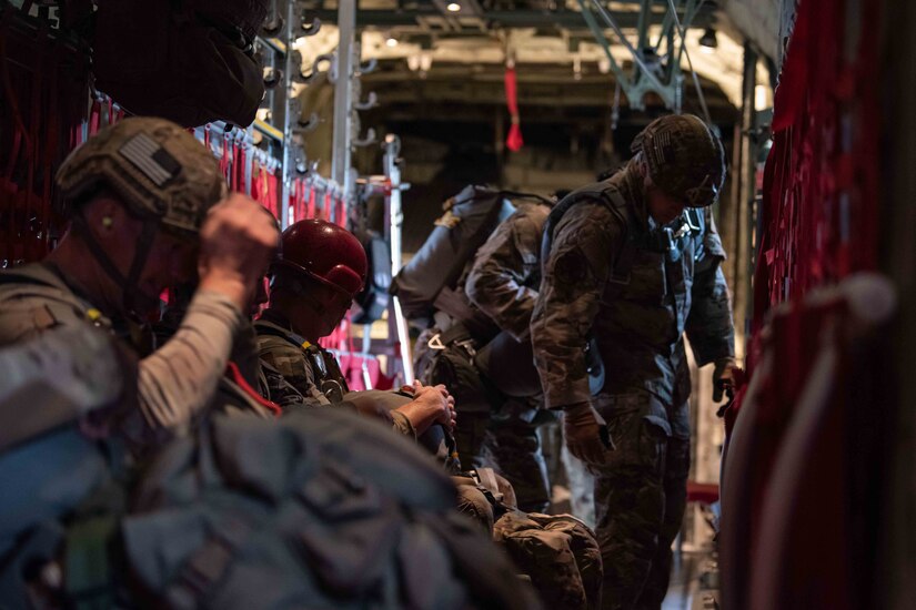 Several uniformed service members prepare to jump from an aircraft.