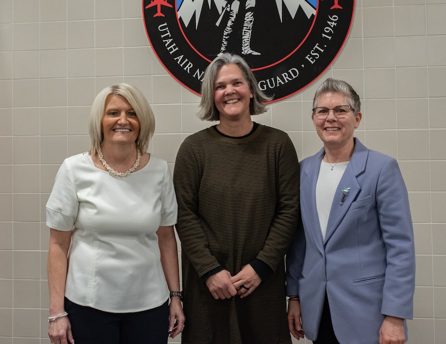 Three retired military women stand and pose for a photo