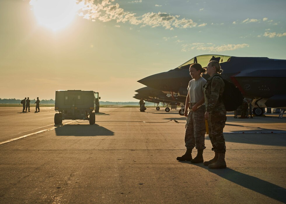 A photo of Airman 1st Class Hannah Piette, Low Observable Technician assigned to the Maintenance Squadron, talking with Staff Sgt. Hailey Sayles, crew chief assigned to the Maintenance Squadron, on the flight line at Northern Lightning, a training exercise held annually at Volk Field, Wis., Aug. 13, 2020.